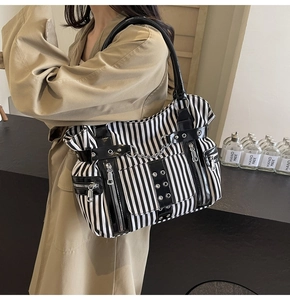 Detail of gothic punk striped tote bag featuring metallic chains and zipper pockets