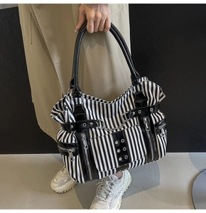 Close-up of gothic punk tote bag showing canvas stripes, silver chains, and metal rivets