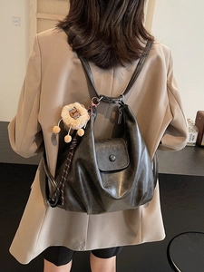 Minimalist black soft leather tote backpack with a cute sheep charm on khaki suit model