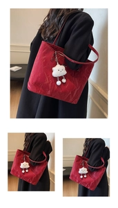 Detail of red wrinkled tote bag with plush cloud charm on a black commuter coat