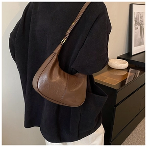 Brown retro leather hobo bag with adjustable strap and gold hardware worn by a model