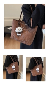 Close-up of brown textured leather tote bag featuring a cute white cloud plush pendant