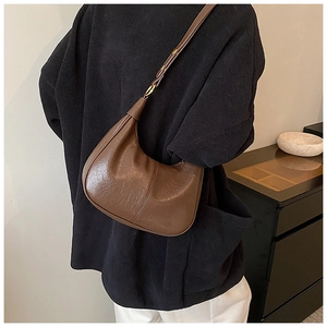 Close-up of a dark brown hobo bag with pleated leather texture and metal buckle detail