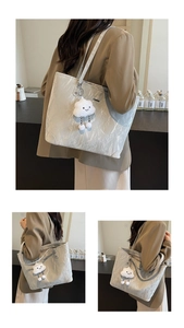 Detail of silver pleated tote bag featuring a cute white cloud plush pendant charm
