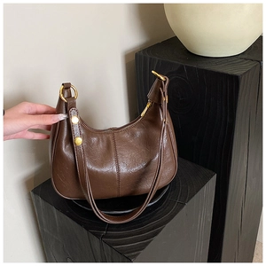 Detail of vintage brown leather shoulder bag with gold hardware on artistic wooden stand