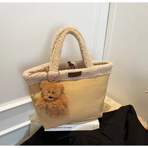 Detail der Lammfell-Eimertasche mit Bärenanhänger und Lederetikett für den Herbst