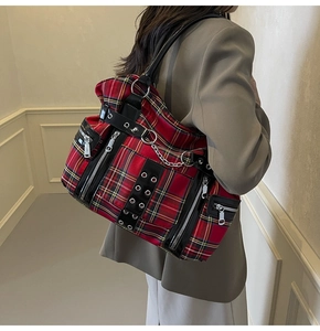 Detail of red plaid punk tote bag with silver metal zippers and decorative chain on shoulder