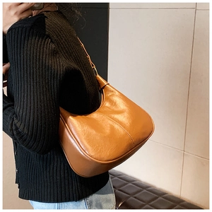Caramel hobo shoulder bag with pleated leather texture worn by a model in casual style