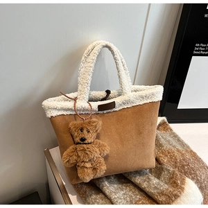 Detailansicht der braunen Wildledertasche mit weißem Lammfellbesatz und Bärenanhänger