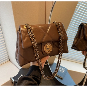 Détail d'un sac matelassé marron rétro avec fermoir doré en forme d'ours et chaîne