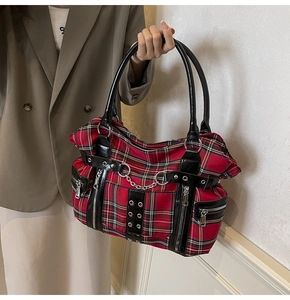 Detail of red plaid punk tote bag with metal chains and multiple zippers on canvas