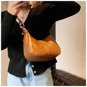 Detail of brown leather hobo bag with contrast white stitching and gold metal ring