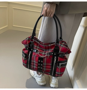 Detail of punk plaid tote bag with silver chains, metallic studs and leather trim straps