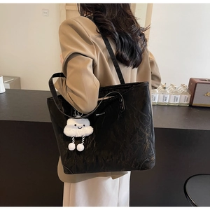 Detail view of black crinkled texture tote bag with a white plush cloud charm accessory