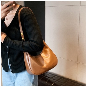 Detail of a brown leather hobo bag showing retro gold metal buckles and stitching