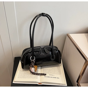 Detail of high-gloss black bowling bag with white stitching and baseball glove charm