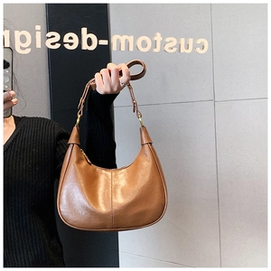 Brown leather crescent bag with decorative stitching and gold zipper detail