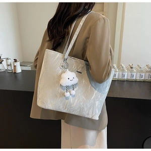 Silver wrinkled tote bag with plush cloud charm shown in a cozy cafe setting