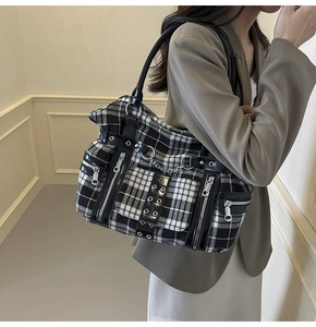 Detail of checkered gothic tote bag featuring silver zippers and punk metal chains