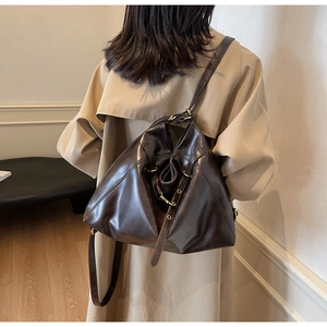 Detail of dark brown leather bag with golden metal hooks and adjustable strap texture