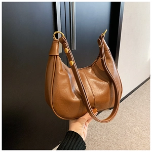 Detail of vintage brown leather hobo bag featuring golden rings and rivet accents