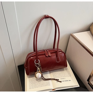 Macro detail of wine red leather handbag with vintage baseball charm on an open book
