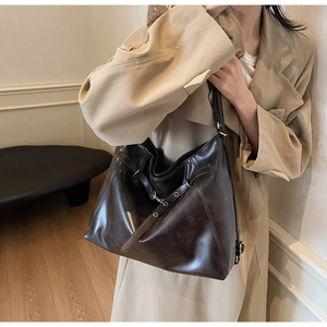 Detail of dark brown faux leather tote bag with vintage texture and gold buckle