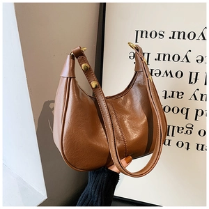 Detailed macro view of the brown leather texture and gold metal studs on the bag strap