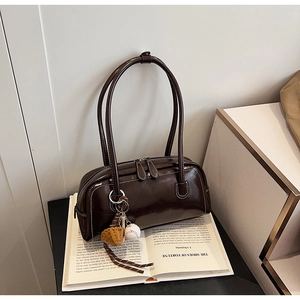 Detail view of a vintage dark brown baguette bag with a baseball themed keychain