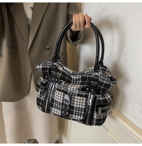 Detail of checkered gothic tote bag featuring silver hardware and durable canvas texture