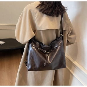 Close-up of large dark brown leather tote bag with vintage texture and gold hardware detail