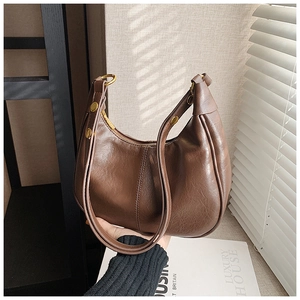 Detail of vintage brown crescent shoulder bag with golden rings and wrinkled faux leather