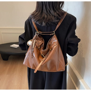 Macro detail of brown vintage leather bucket bag with metallic buckle and baseball charm