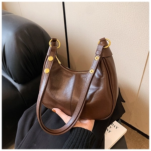 Close-up of brown vintage hobo bag with pleated texture and gold metal ring detail