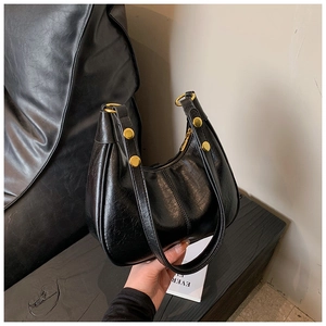 Detail of black crescent moon bag with glossy leather and golden metal ring ornaments