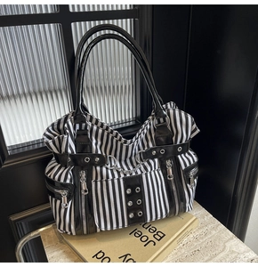 Detail of gothic punk striped canvas tote with silver zippers and metal chains