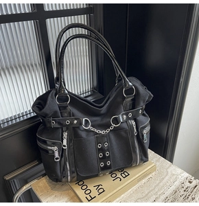 Detail view of canvas punk tote bag featuring metal chains and decorative eyelets