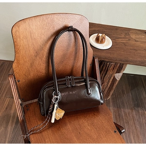 Detail of vintage brown leather boston bag with baseball charms on a wooden chair
