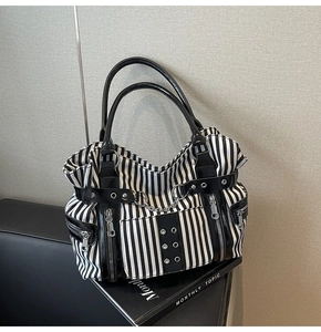 Detail view of canvas striped tote with silver chains and functional zipper pockets