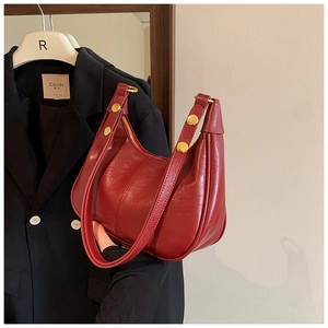 Detail shot of a dark red hobo bag with glossy finish and elegant golden hardware