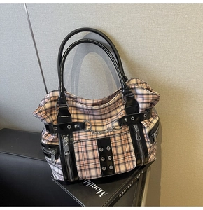 Detail of gothic punk plaid tote bag featuring black patent leather straps and metal rivets