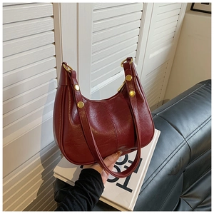 Detail of dark red hobo bag with oil wax leather texture and gold metal rivets