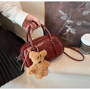 Dettaglio borsa bowling in pelle PU rosso scuro con ciondolo a forma di orso