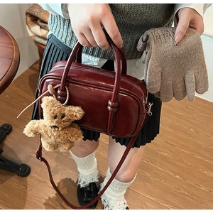 Dettaglio borsa bowling bordeaux in pelle PU con ciondolo a forma di orsetto di peluche