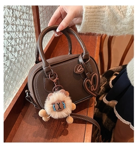 Detail of dark brown leather Boston bag with white stitching and cute lamb charm