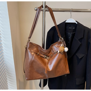 Detailed close-up of brown PU leather tote bag with gold hardware and baseball charm