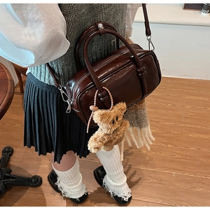 Dettaglio di una borsa Boston vintage in pelle PU marrone con un simpatico orsetto peluche