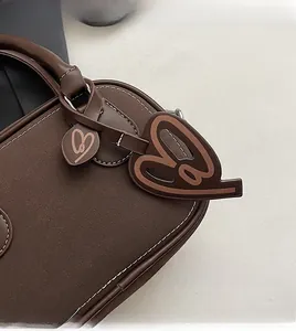 Detailed close-up of brown Boston bag showing heart charm and white contrast stitching