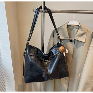 Detail of a large black vintage tote bag with metal buckles and decorative pendants