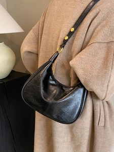 Chic black crescent leather shoulder bag with gold hardware shown on a model